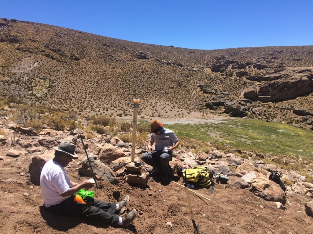 Photo: Two people work in a desert landscape.