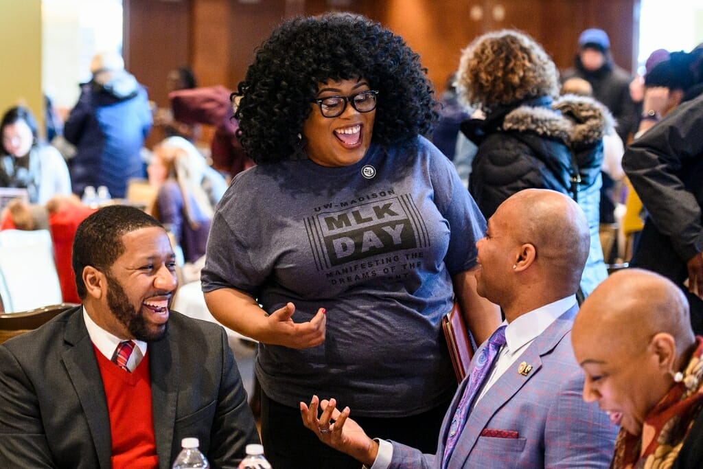 Four people laugh and talk at a table.