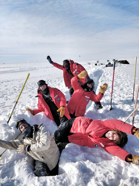 Photo: Hands and arms raised in celebration on completing the first 30-meter cable trench for a new radio antenna to support future expansions of IceCube in January, 2019.