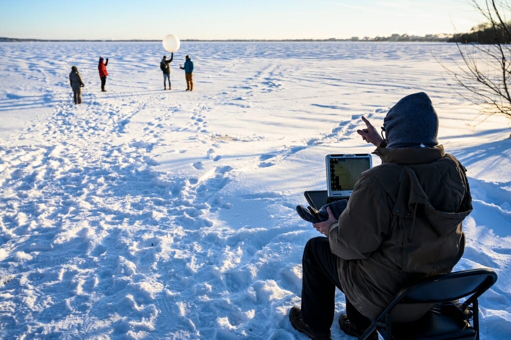 Students stand on frozen Lake Mendota poised to launch the weather balloon, now equipped with the radiosonde. Petty checked that the instrument was transmitting data to his computer and gave the students instructions prior to launch.