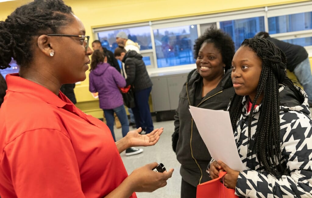 Photo: A woman talks with two students.