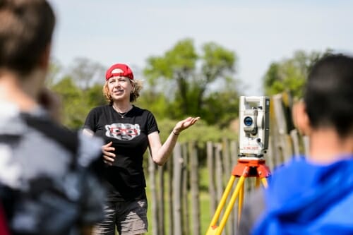 Photo: An archeologist gestures at an outdoor dig site.