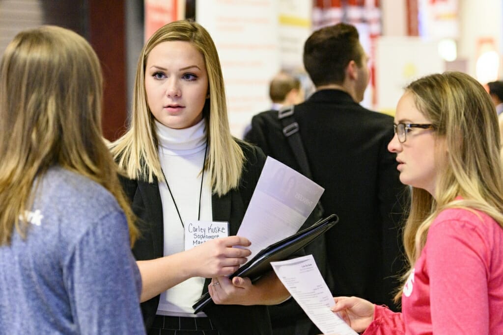 UW undergraduate Carley Kuske (center)  talks with recruiters from Kimberly Clark.