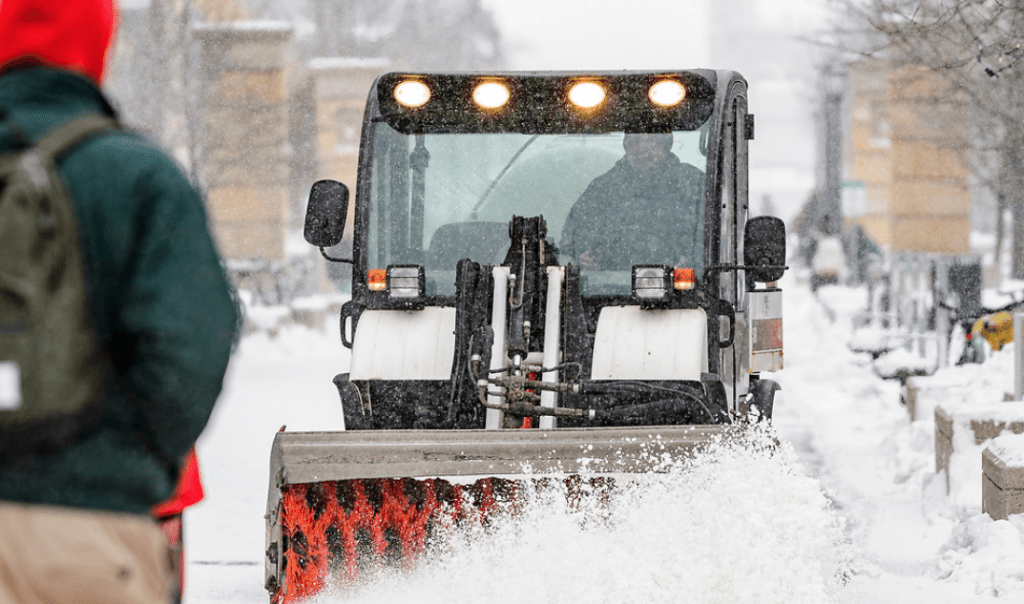 UW grounds crew members work to clear snow from the sidewalks on East Campus Mall at the University of Wisconsin–Madison