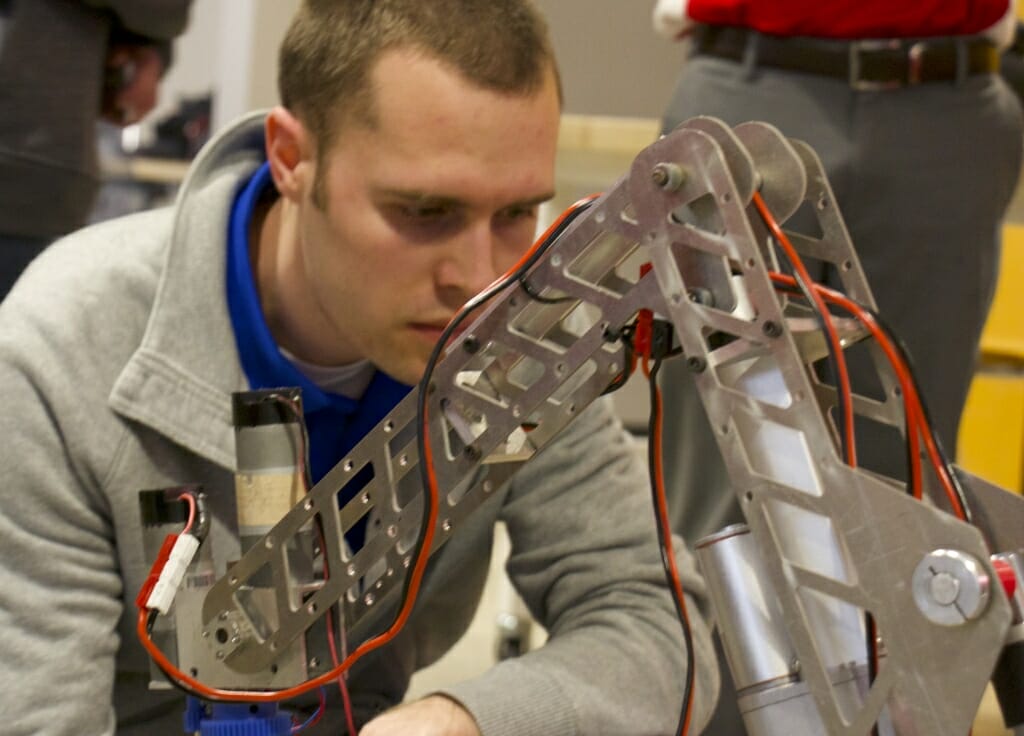 Photo: A man looks over a robotic thing.