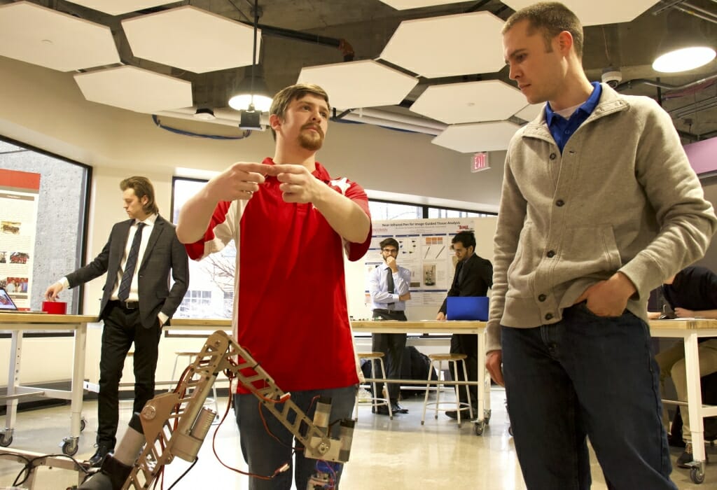 Photo: Student looks over a robotic device.