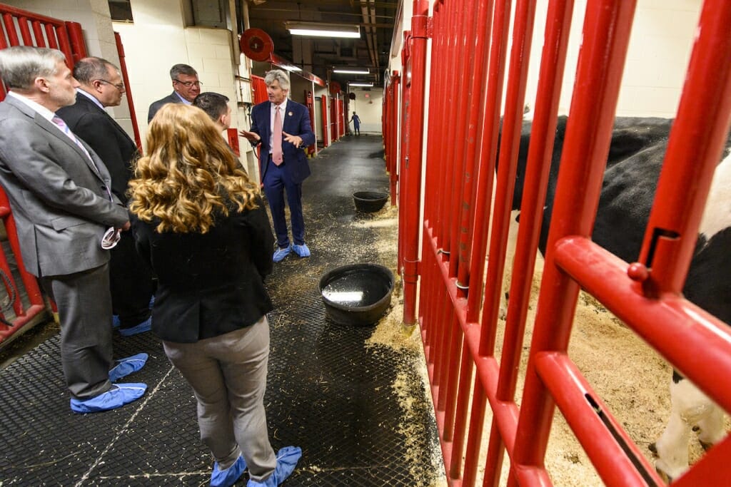 Photo: Man talking with group of people next to an animal's cage.