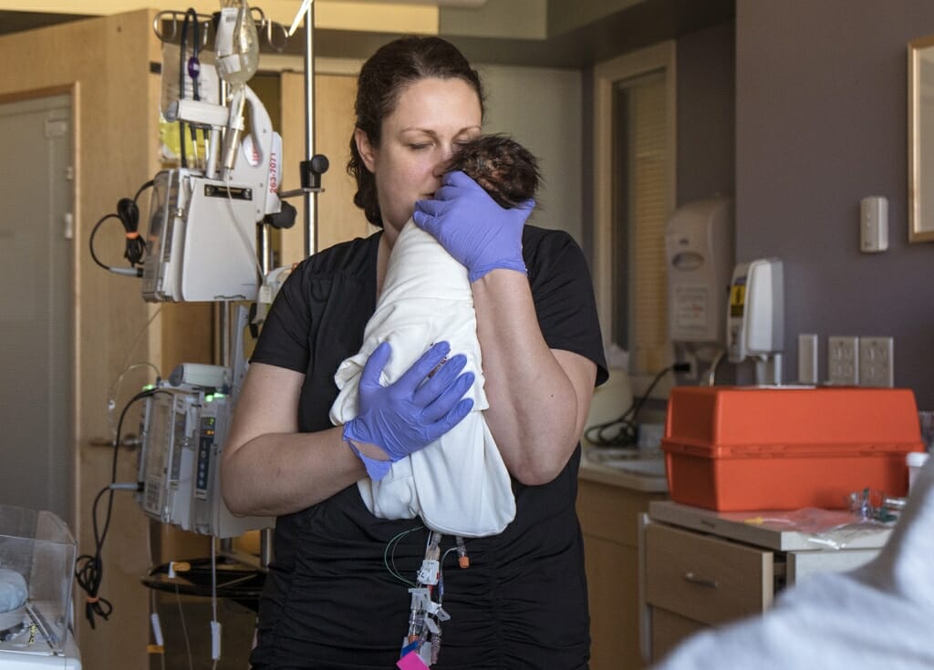 “This baby boy is about to be held by his dad for the very first time,” says Alison Schlimgen, neonatal intensive care unit (NICU) nurse. “I’ll always remember the day this picture was taken. It is one of those extraordinary moments that happen every so often in life that leave you feeling breathless.”
This baby was born critically ill. For weeks, hospital staff cared for him in the NICU, but his condition continued to worsen. 
Bu then the baby's condition suddenly began to improve, vital signs stabilized and spontaneous breathing began to occur without the help of a ventilator. 
On the day of the photo, Schlimgen was about to hand this boy to his father for the first time.

“As I picked this baby up, I was suddenly and completely overtaken by emotion,” says Schlimgen. “What was happening in this child’s life was something beyond a scientific or medical explanation. I was witnessing a miracle.”