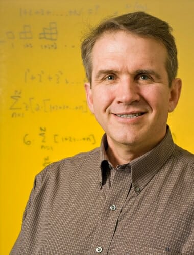 Photo: Portrait of Terry Millar standing in front of a whiteboard with writing on it