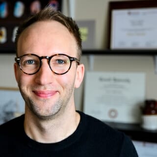 Photo: Evan Polman in his office in front framed certificate