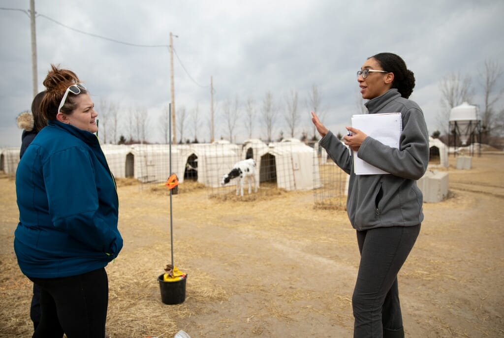 Photo: Rekia talking with a woman in front of calve enclosures