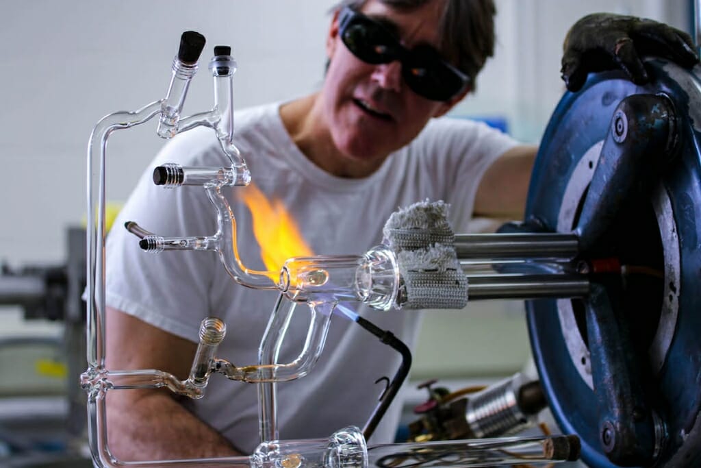 Photo: Drier in dark goggles working with flame on glass instrument