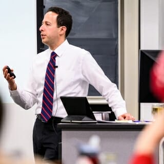 Photo: Robert Yablon standing at a lectern speaking to class