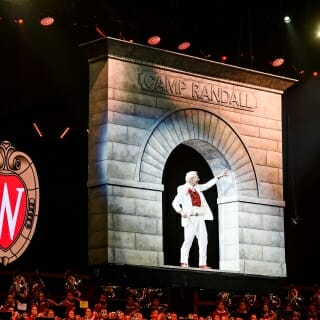 Photo: Leckrone waves to the crowd under a model of an arch.