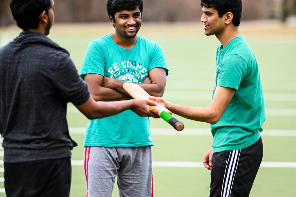 Photo: One man handing bat to another