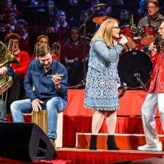 Photo: A young woman sings with band director Mike Leckrone, as two others accompany them.