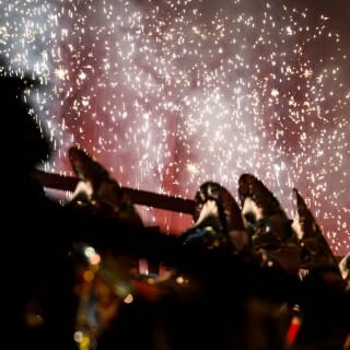 Photo: Tuba players are silhouetted by fireworks.