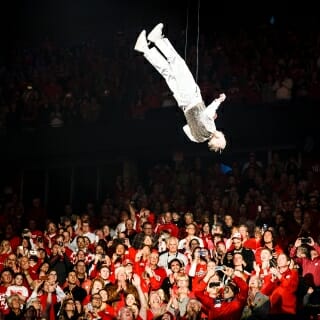 Photo: Leckrone is shown suspended above the stage on wires, upside down.