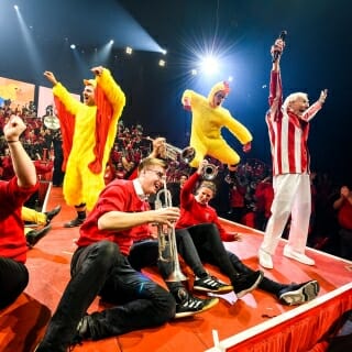 Photo: Band members leap and dance, two of them wearing chicken costumes.