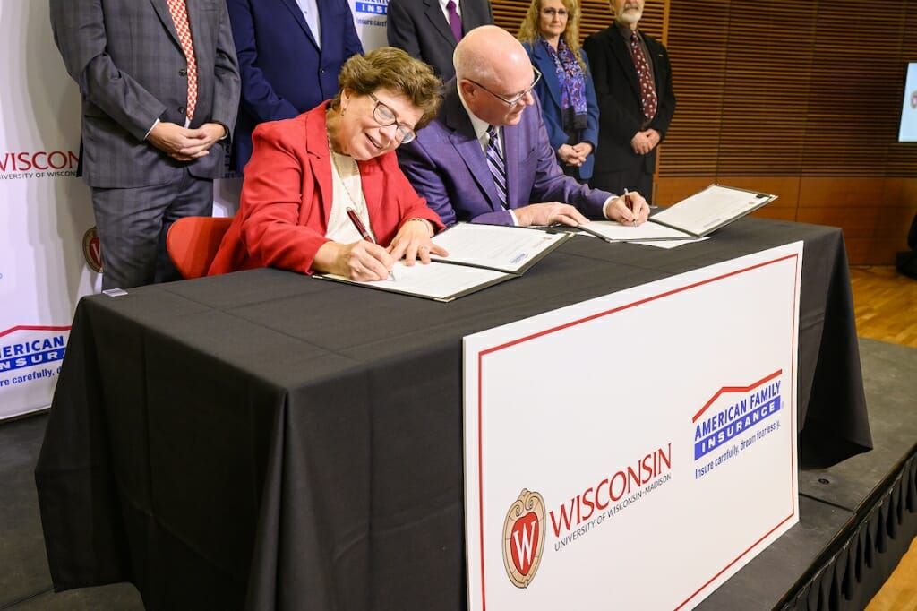 Photo: Blank and Salzwedel sitting at a table signing documents