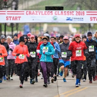 Photo: Runners start the Crazylegs race, with a banner above them and snow falling.