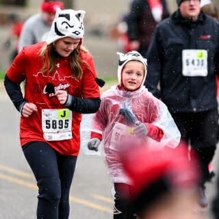 A young woman and a girl wearing Badger hats run.