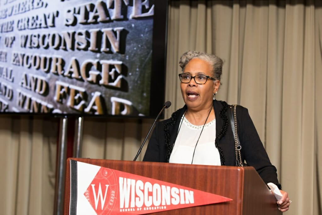 Photo: Billings speaking at podium with sifting and winnowing plaque on screen