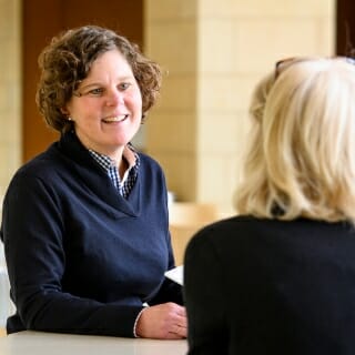 Photo: Karen sitting at table talking to unidentified person