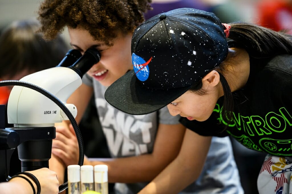 Photo: Two boys peer through a microscope.