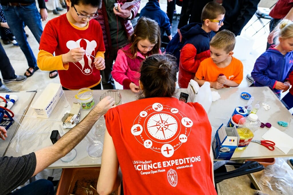 Photo: Kids surround a table with science activities.