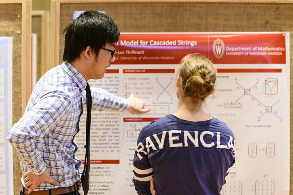 Photo: A student points to his poster board.