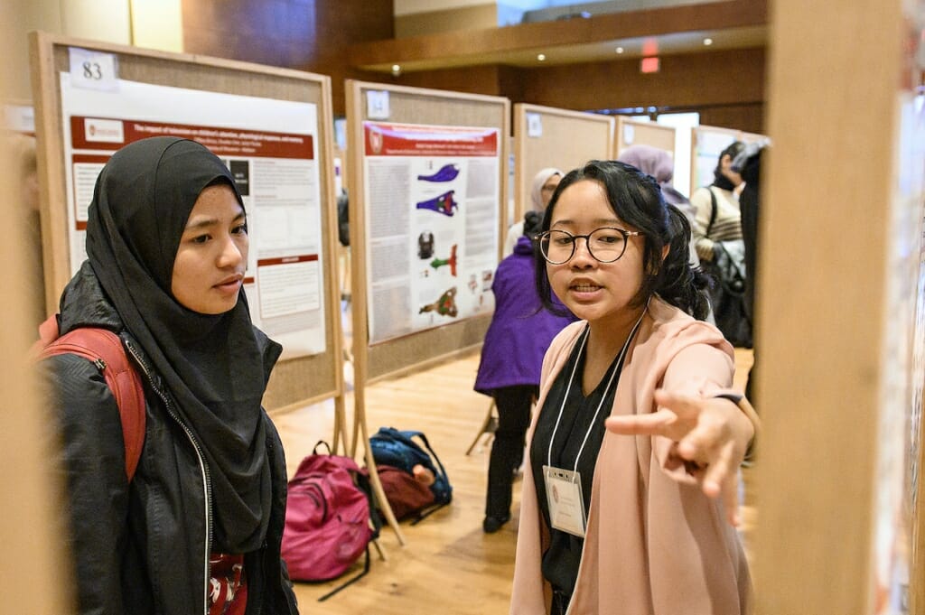 Photo: Woman explains her project and points to a board.