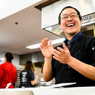 Photo: A man claps his hands in a kitchen.