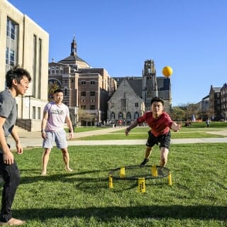 Photo: Three men play a ballgame on grass.