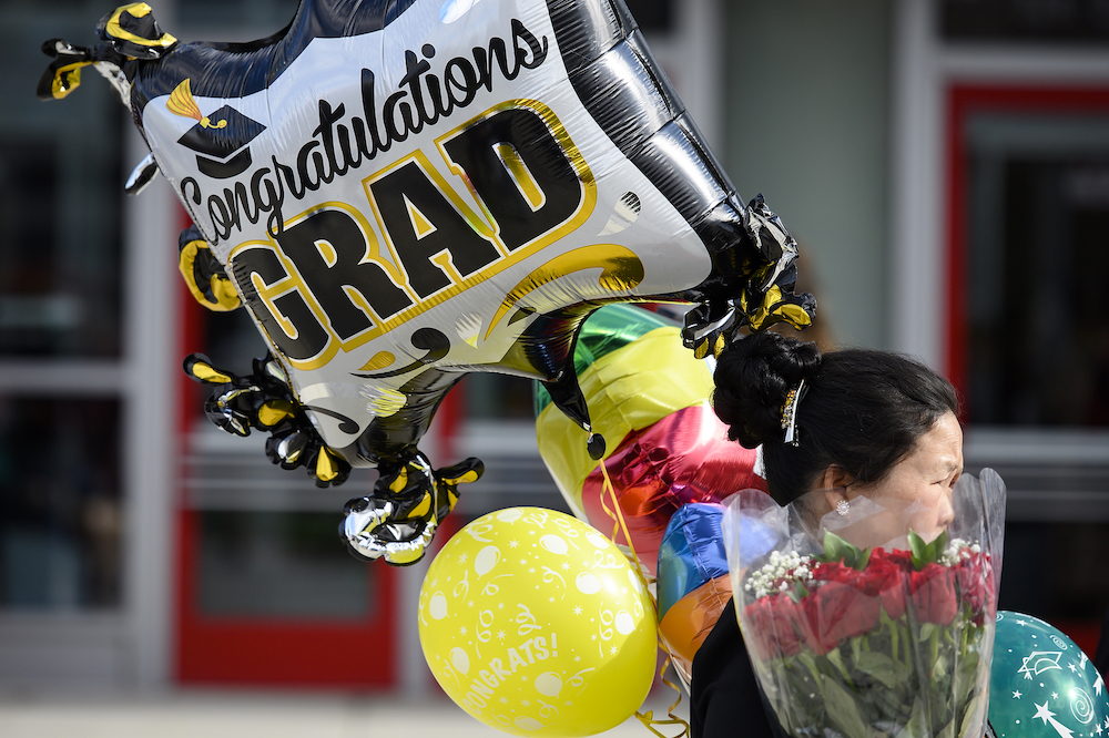 Photo of a woman carrying balloons and flowers.