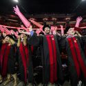 Photo of graduates waving inflated medical gloves.