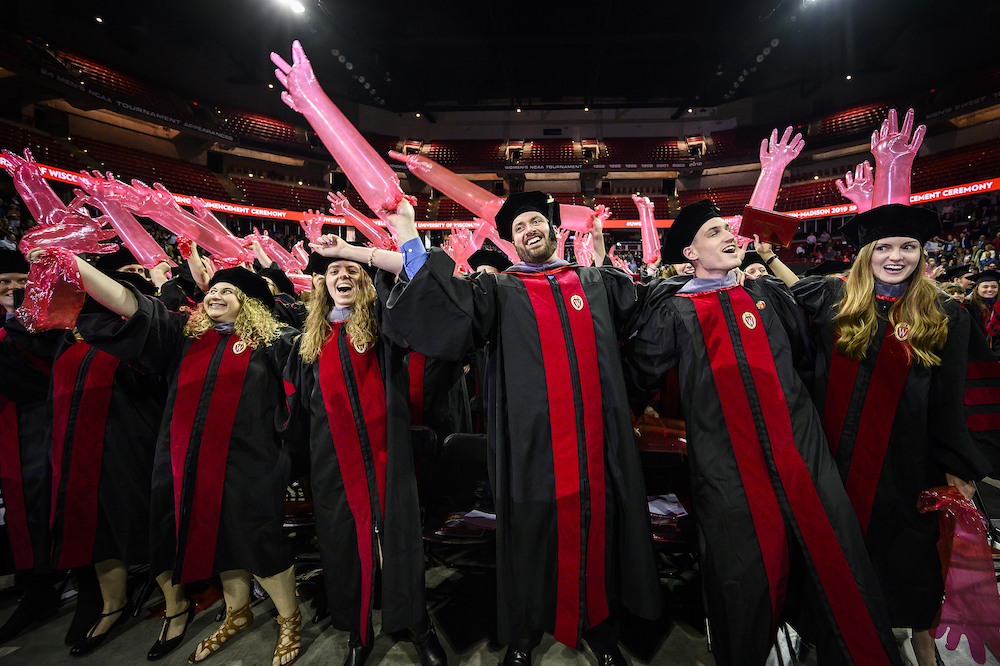 Photo of graduates waving inflated medical gloves.