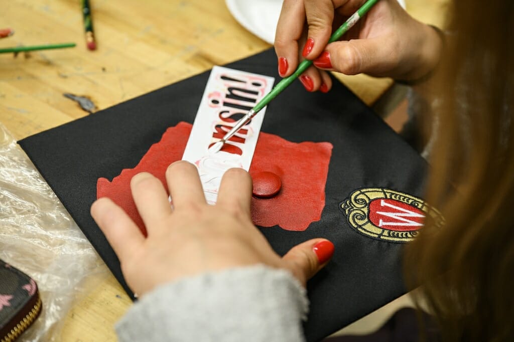 Photo: A woman stencils letters ons her cap.