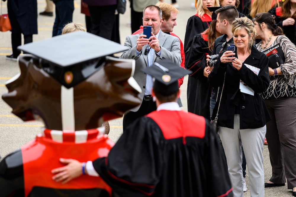 Photo of graduate with his arm around Graduation Bucky