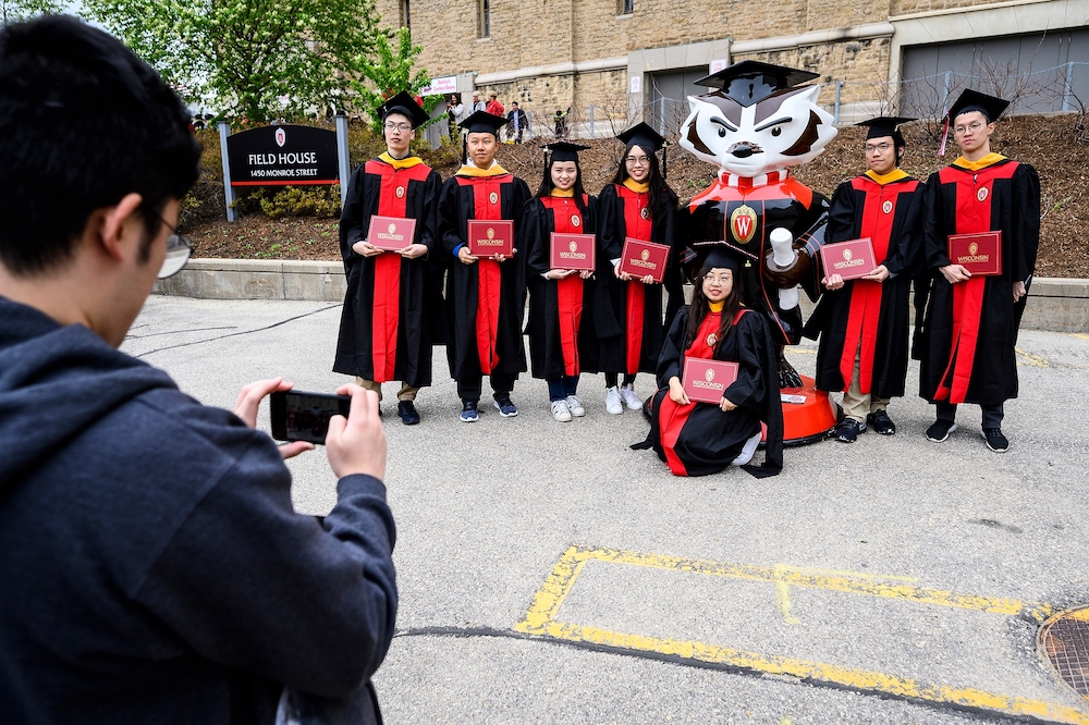 A group of students poses with the Graduation Bucky statue.