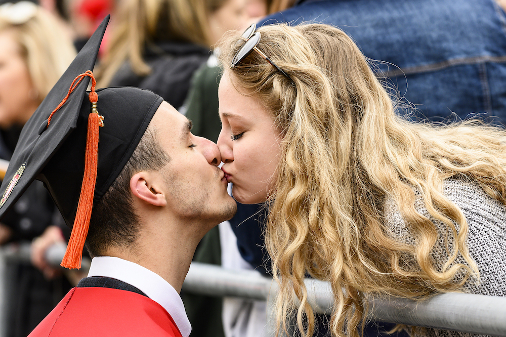 A graduate and his girlfriend share a kiss.