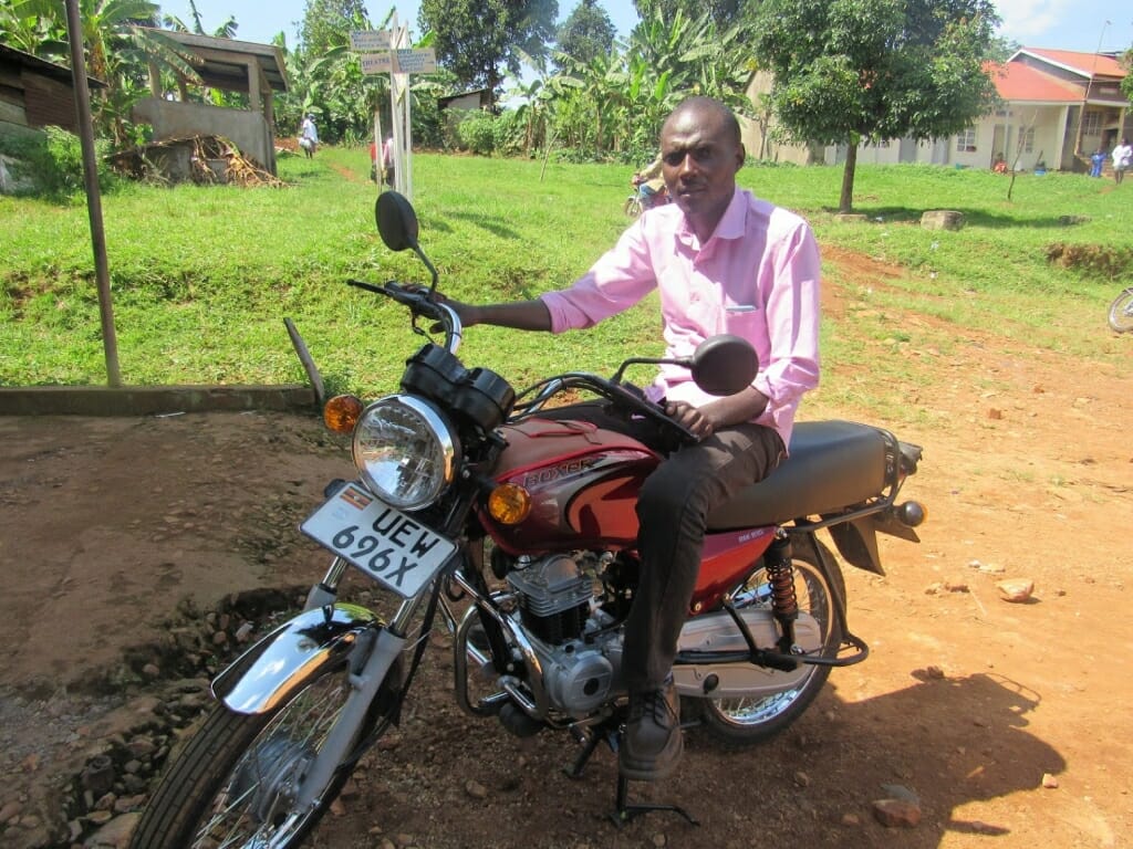 Photo: A man sits on a motorcycle in an African village.