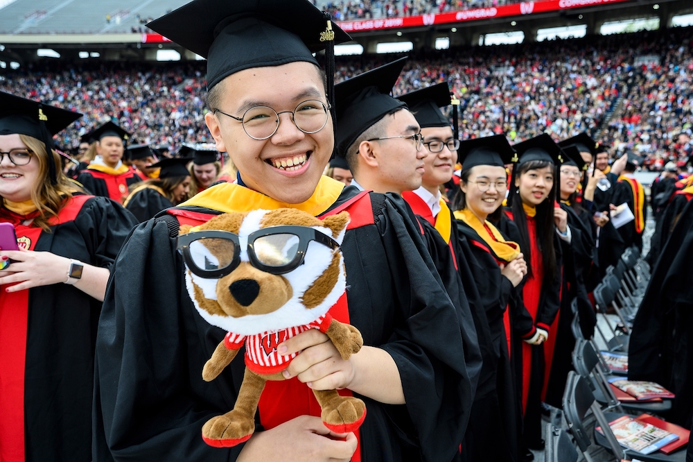 Photo of a graduate holding a plush Bucky Badger