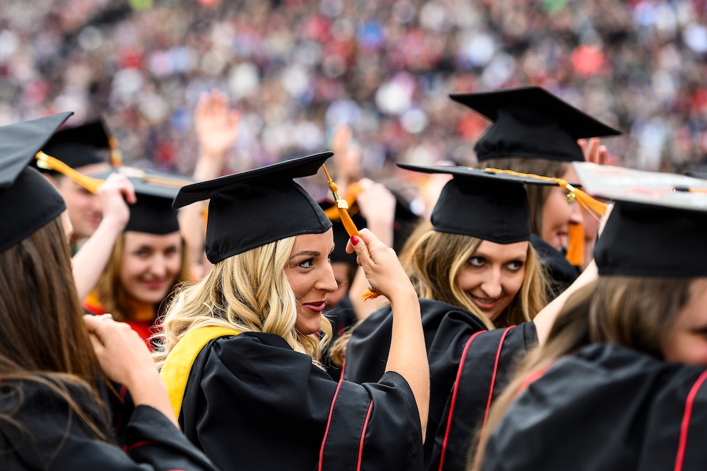 Photo of graduates moving the tassels on their mortarboards.