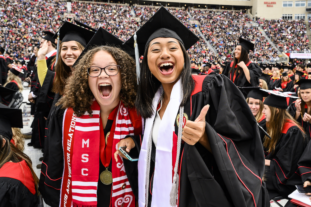 Photo of two graduates smiling and giving a thumbs up