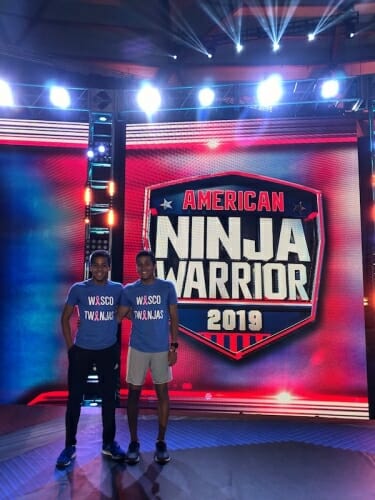 Photo: Green twins standing in front of Ninja show logo