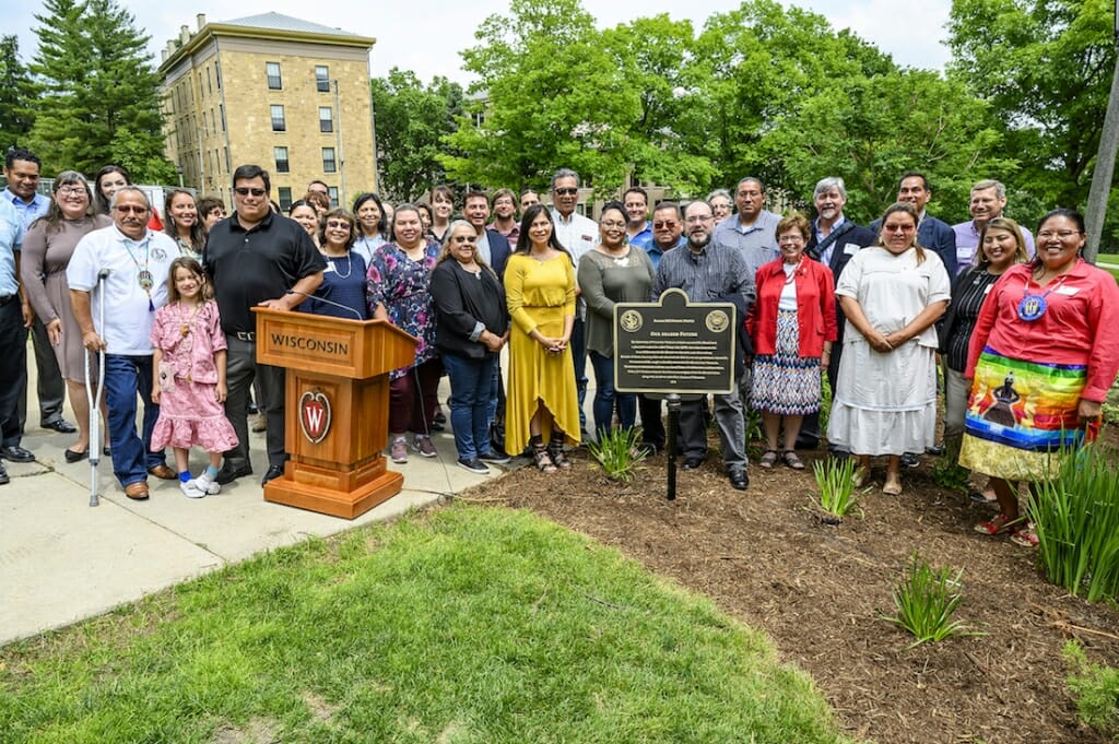 Photo: Group photo of participants standing behind plaque