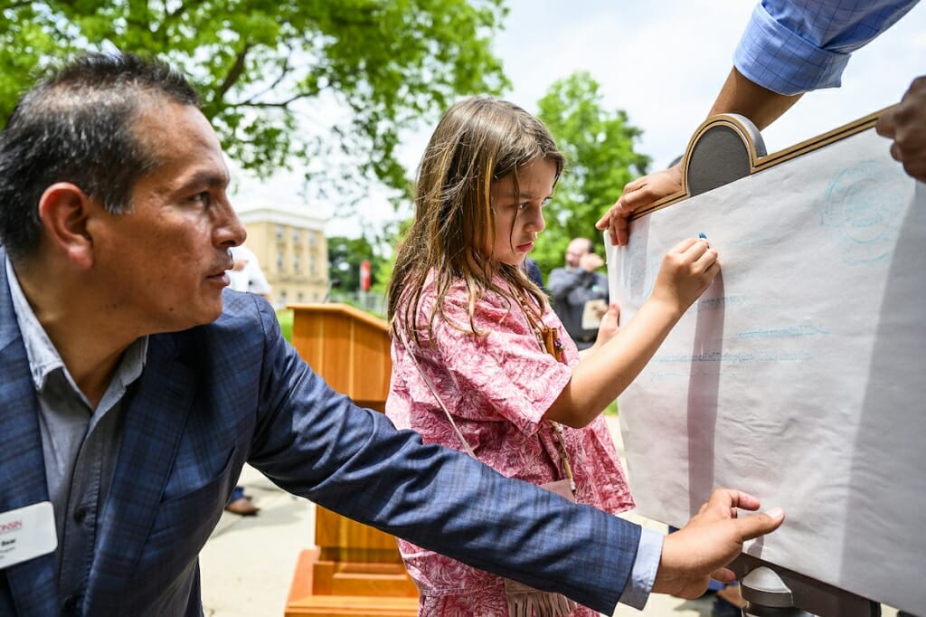 Photo: Aaron helping hold paper on plaque while Demetria rubs with crayon