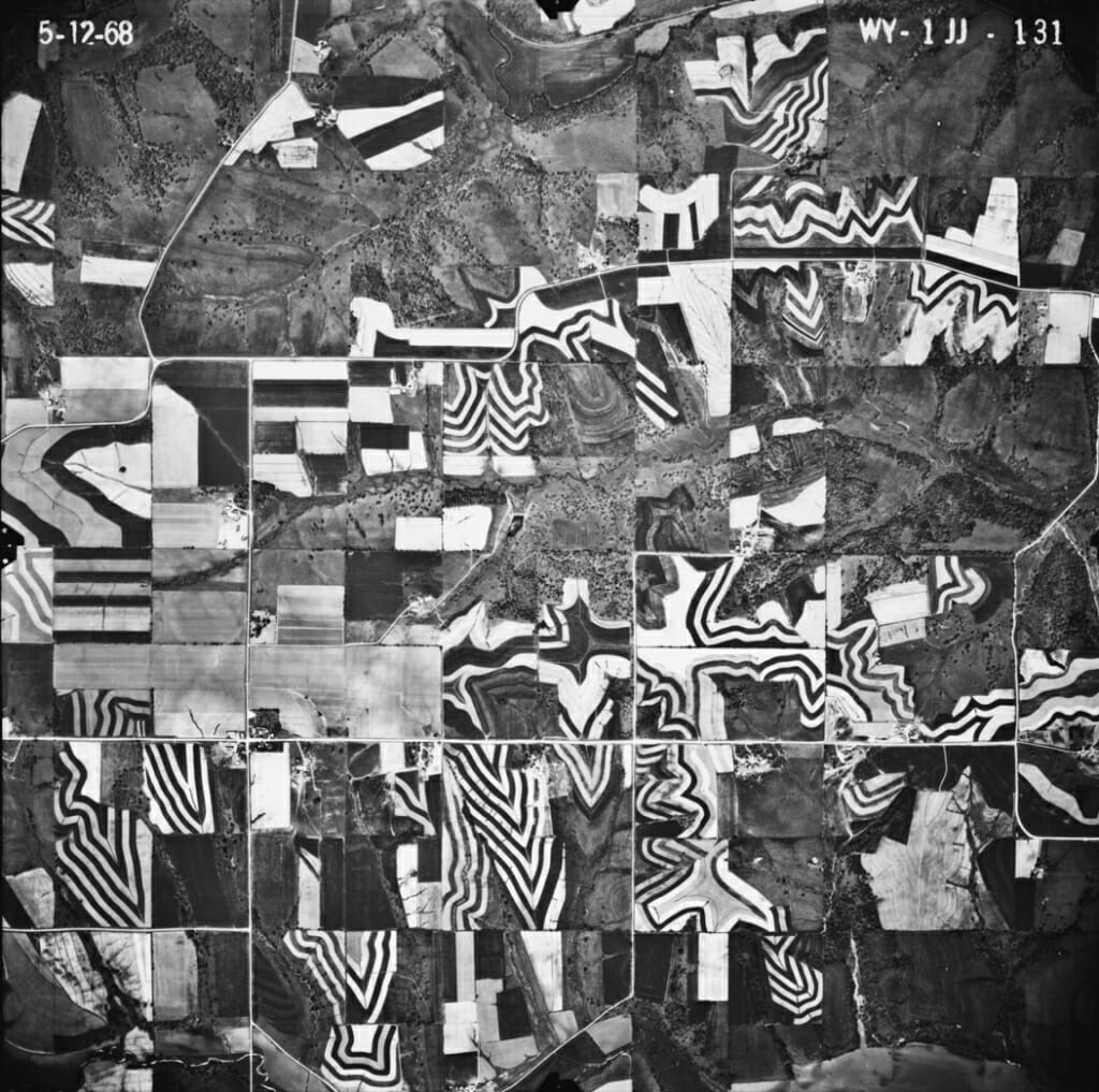 Photo: An aerial photo of farm fields with a distinctive black-and-white striped pattern characteristic of strip cropping.