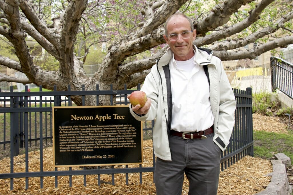 Photo: A man standing in front of an apple tree.